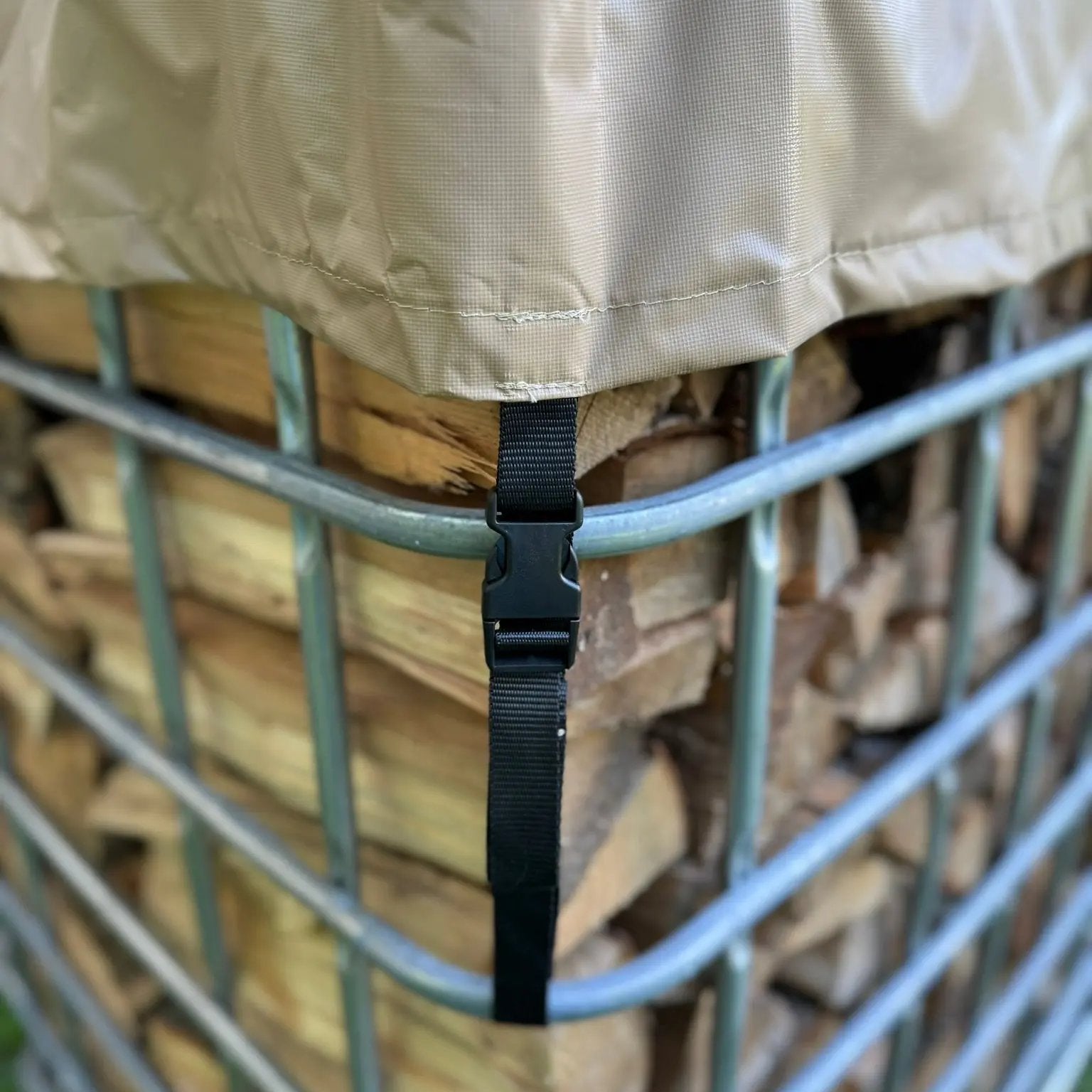 Beige firewood cover on a metal IBC tote firewood holder with buckle on strap