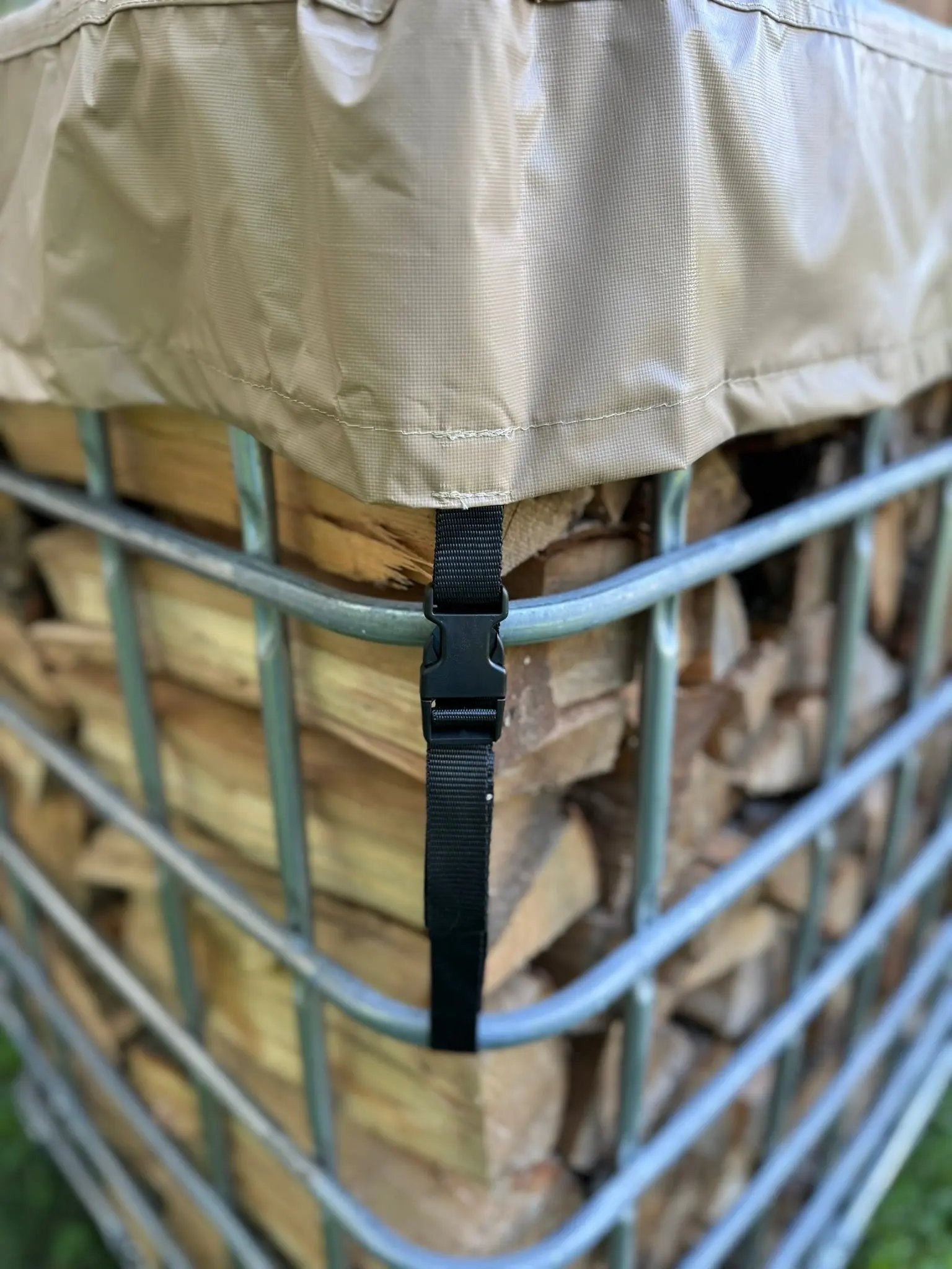 Beige firewood cover on a metal IBC tote firewood holder with buckle on strap