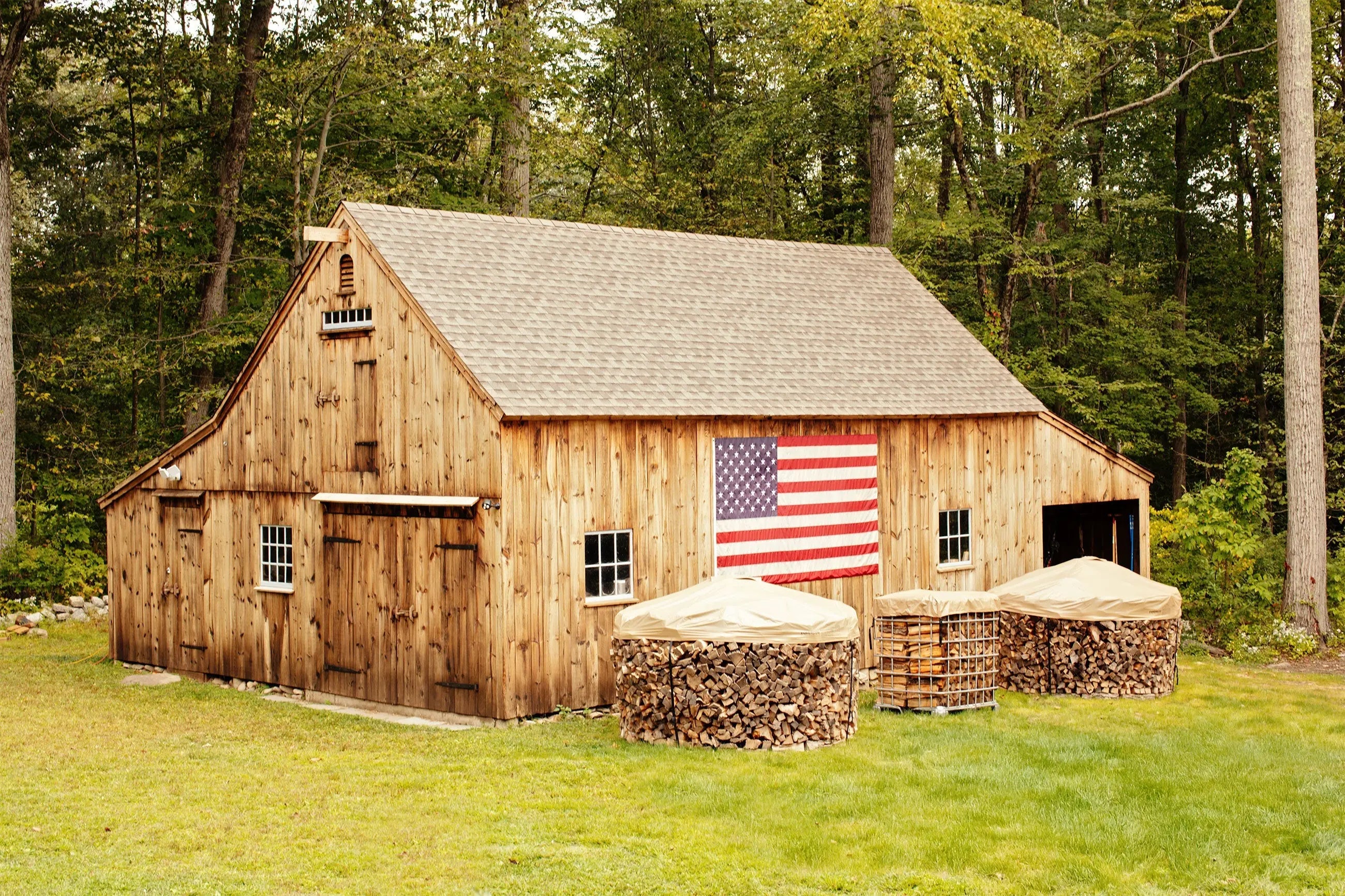 Barn with american flag and Cordwood Covers in front